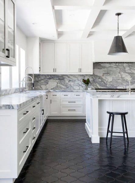 Elegant kitchen with black patterned tile flooring, white cabinetry, marble countertops, and a striking marble backsplash, complemented by modern lighting