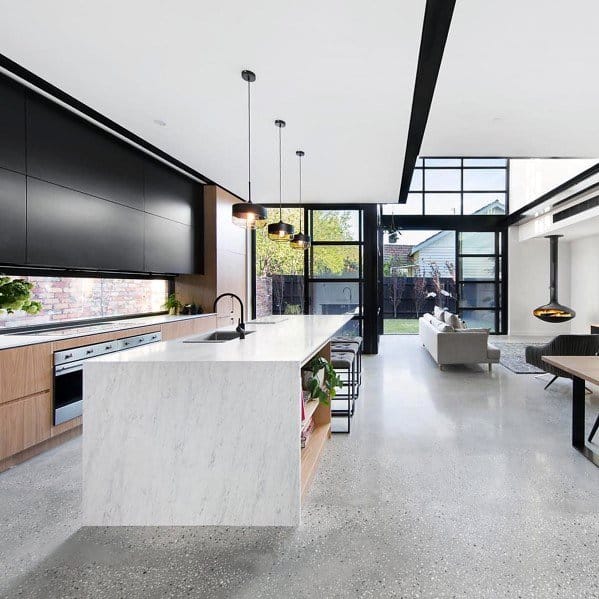 Contemporary kitchen with polished concrete flooring, sleek white marble island, black cabinetry, and large windows offering plenty of natural light