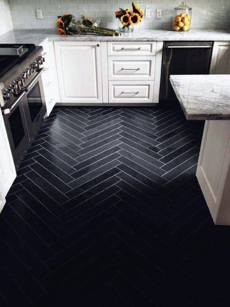 Sophisticated kitchen with black herringbone tile flooring, white cabinetry, and marble countertops, creating a chic and modern atmosphere