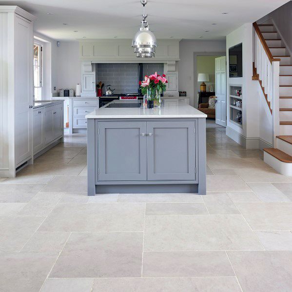 Charming kitchen with light stone tile flooring, gray cabinetry, and a central island, featuring modern pendant lighting and a cozy atmosphere