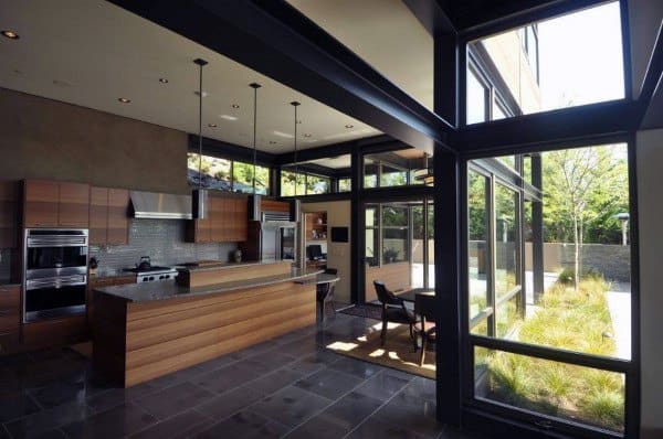 Modern kitchen with wooden cabinets, central island, large windows showcasing an island view of outdoor greenery