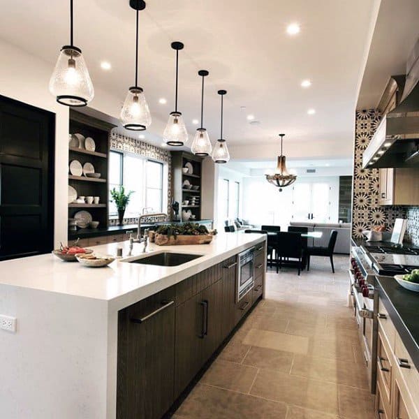 Modern kitchen with hanging lights, a central island, and open shelving; spacious island dining area in the background