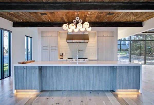 Modern kitchen with light wood island, rustic ceiling, large windows, and cluster pendant lighting.