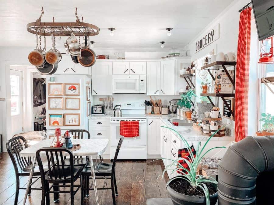 white country kitchen dining table four black chairs hardwood floor floating wood shelves hanging pots