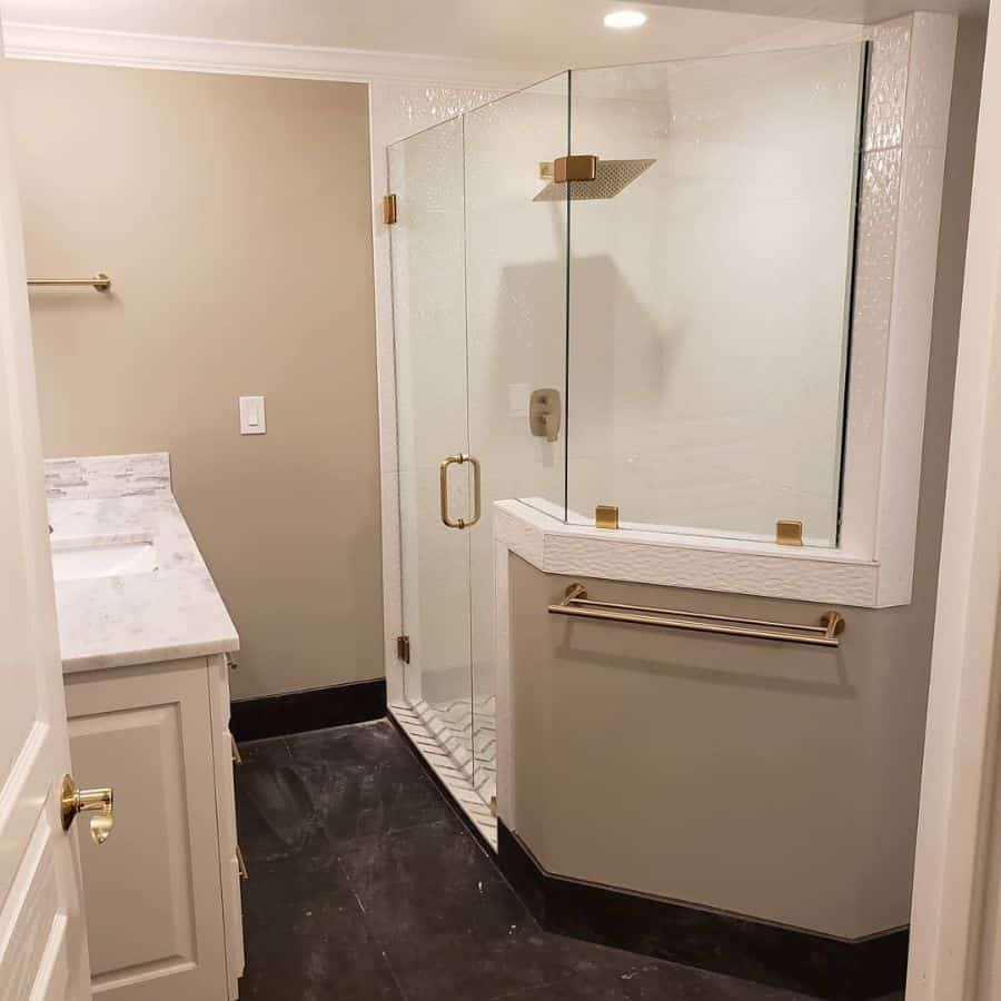 Basement bathroom with large glass shower, marble countertop, and beige walls.