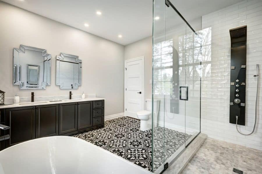 Spacious bathroom with freestanding tub, glass shower, black vanity, and patterned tile floor.