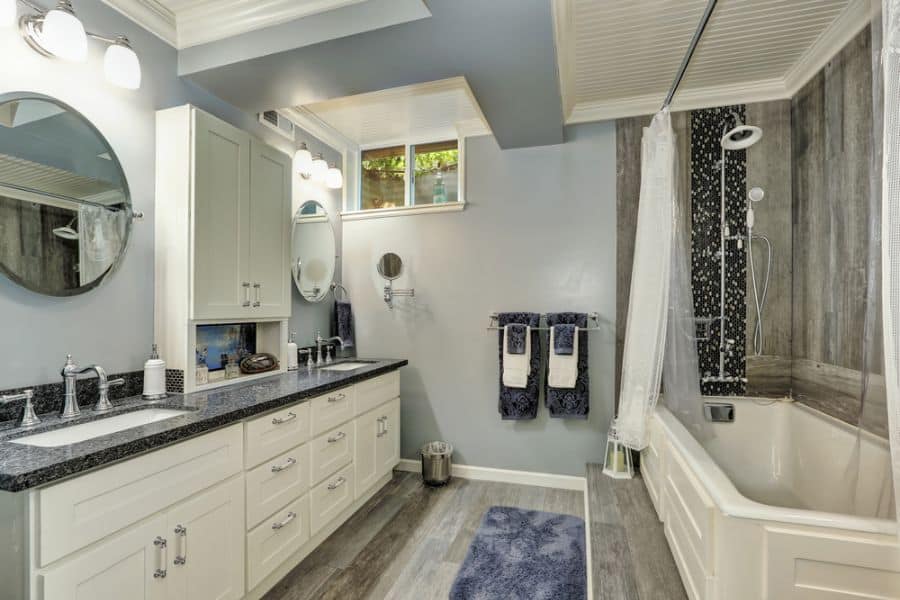 Large basement bathroom with double vanity, soaking tub, and blue accents on walls and towels.