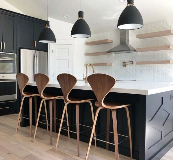 Stylish kitchen with large black vintage-inspired pendant lights above a white marble island, complemented by sleek wooden bar stools and dark cabinetry