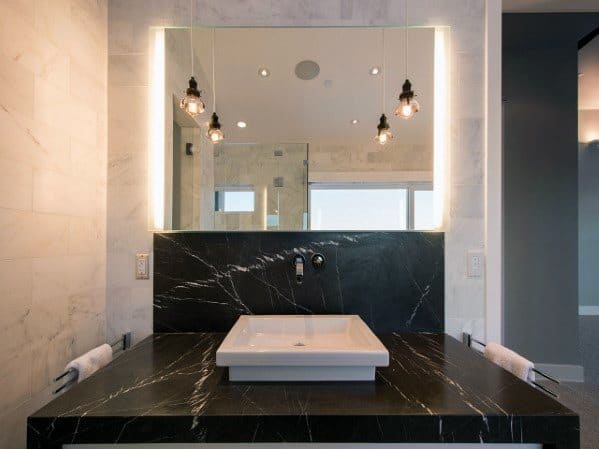 Bathroom with black granite backsplash, square sink, and illuminated mirror.