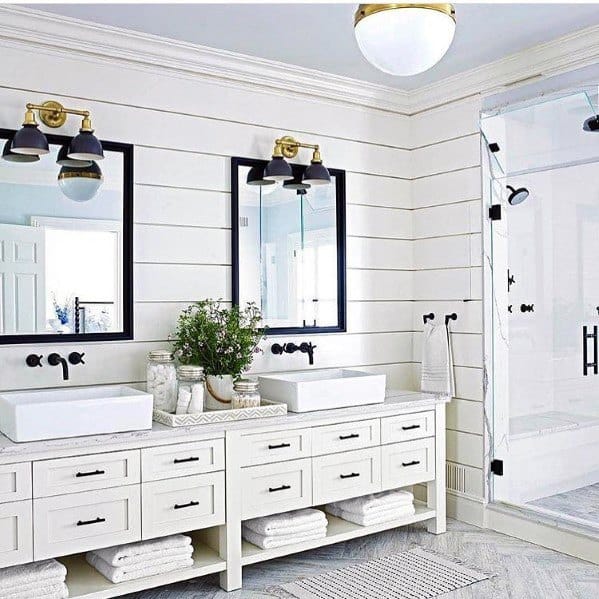 White double vanity with black framed mirrors, modern lighting, and large glass shower.