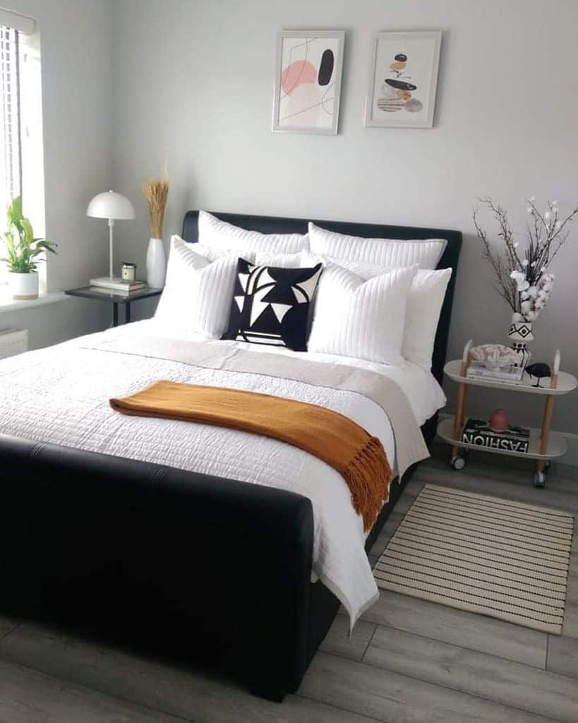 Modern bedroom with abstract wall art, cozy bedding, and an orange throw.