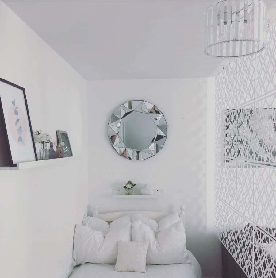 White bedroom with floral throw pillows and grey headboard.