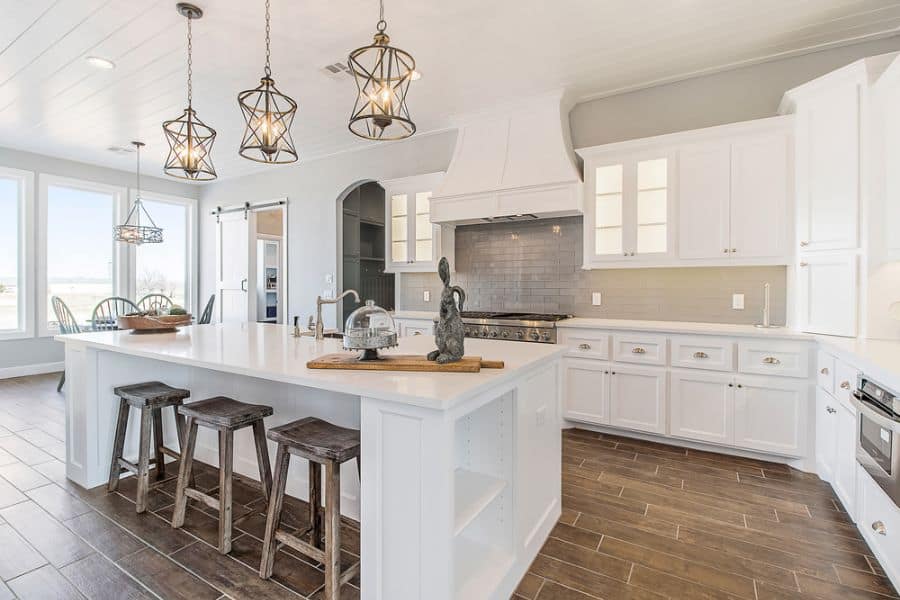 large white kitchen cabinet with stone flooring and track lighting 