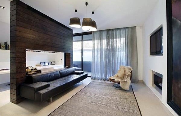 Open modern living room with black leather sofa, large windows, and minimalist decor.