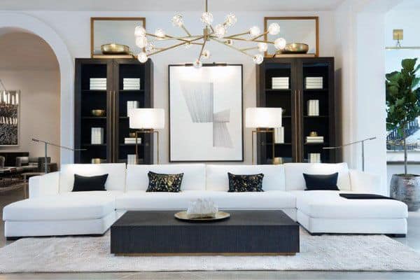 Modern living room with a spacious white sofa, abstract art, dark shelves, and a stylish chandelier