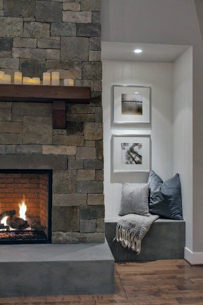 A cozy rustic living room nook with a stone fireplace, soft seating, and framed artwork, creating a peaceful and inviting corner