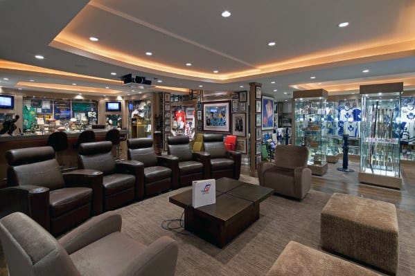 Spacious home theater with leather recliners, sports memorabilia displays, and modern lighting.