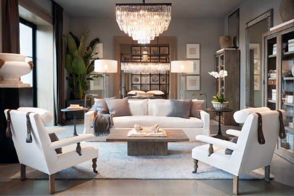 Elegant living room with a chandelier, white sofas, armchairs, a coffee table, and decorative plants