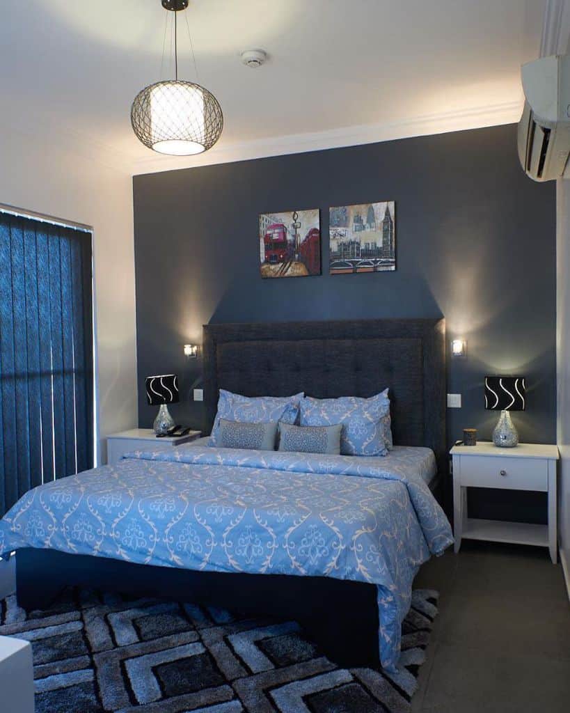 Blue bedroom with London-themed wall art, patterned bedding, and white bedside tables.