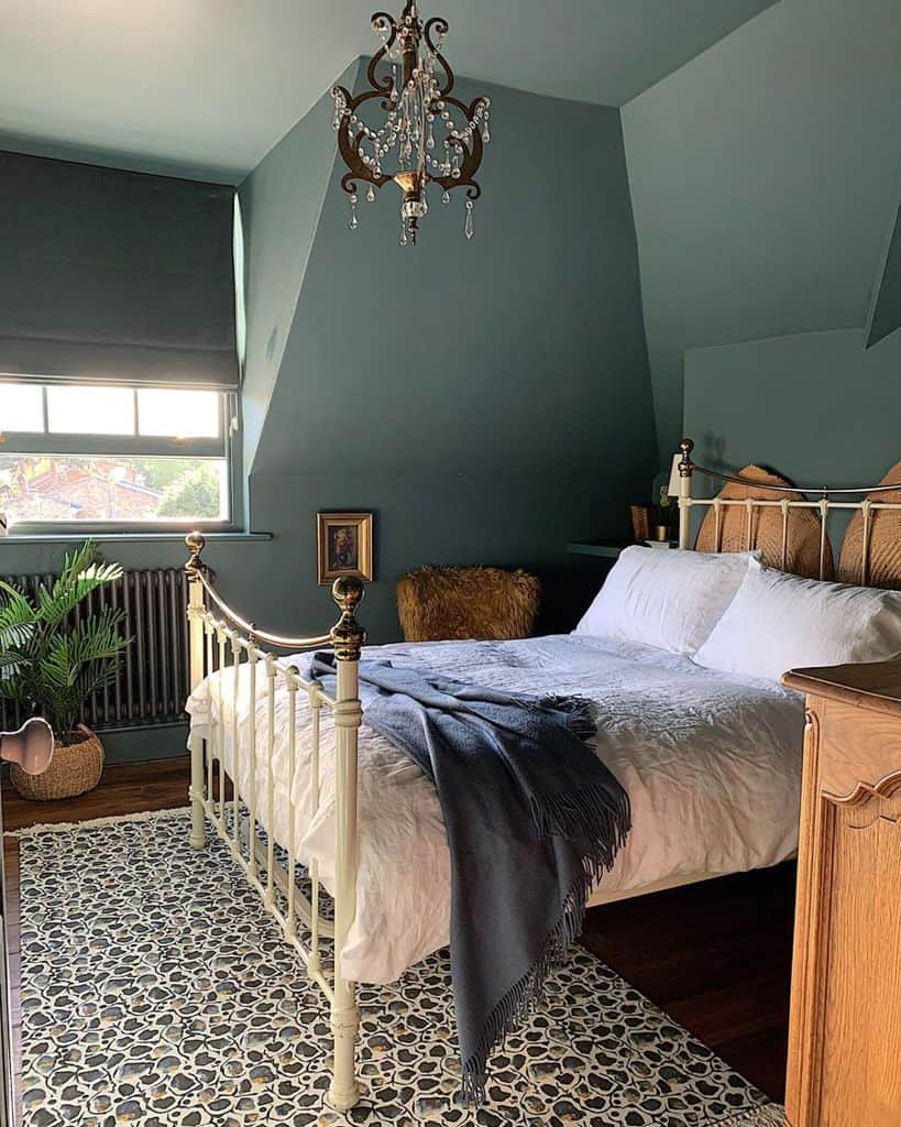 Vintage green bedroom with four-poster bed, chandelier, and patterned rug.