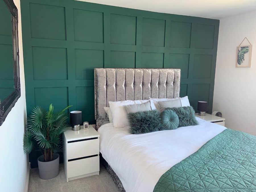 Luxury green bedroom with tufted headboard, white bedside tables, and potted plants.