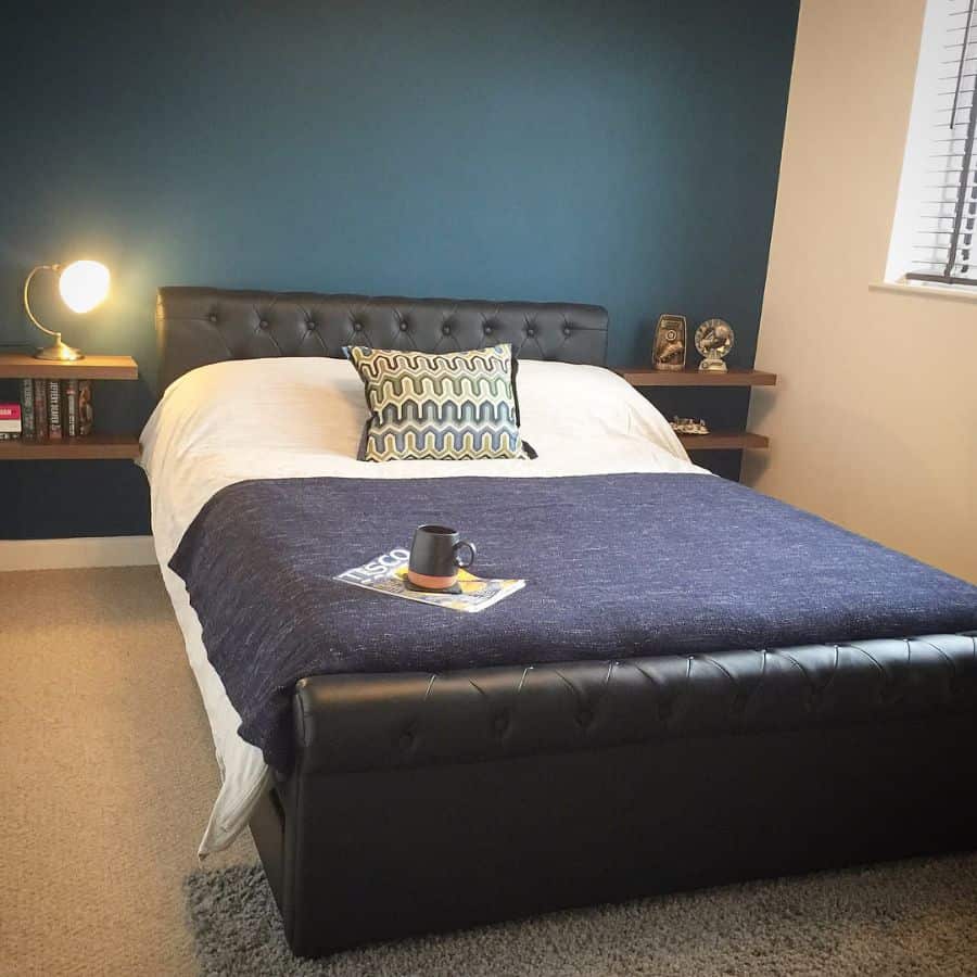 Cozy bedroom with blue feature wall, leather headboard, and floating shelves.