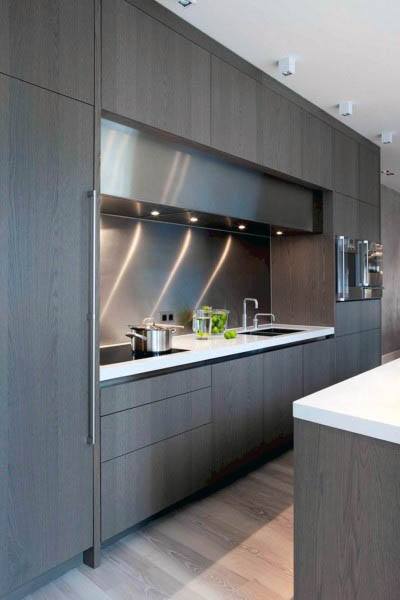 Modern kitchen with dark wood cabinets, stainless steel backsplash, and white countertops.