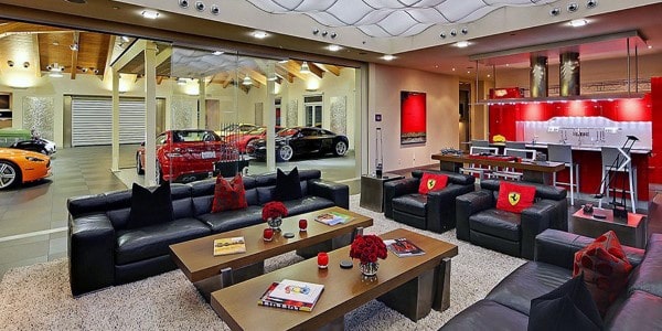 Luxury garage bar with Ferrari-themed decor, glass wall showcasing sports cars, and modern seating area.