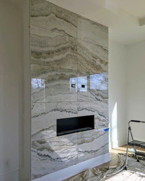 Contemporary gas fireplace with polished beige marble tiles featuring natural wave patterns.