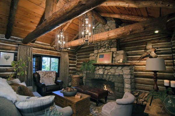 Rustic log cabin living room with stone fireplace, exposed beams, leather chairs, and American flag decor