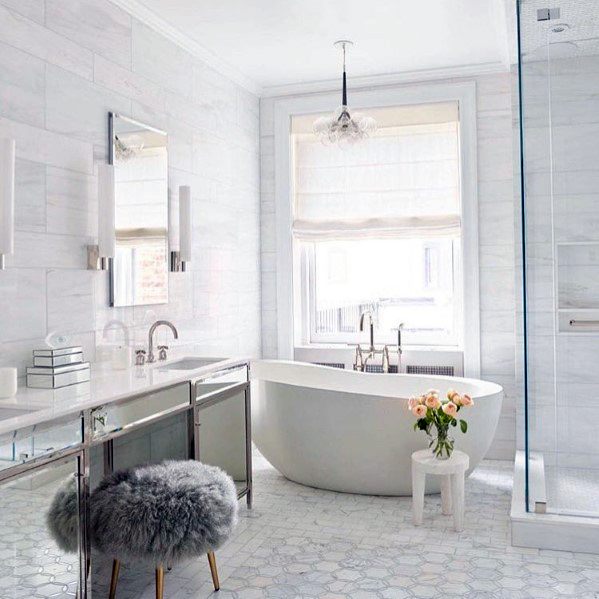 Modern bathroom with a sleek white bathtub, fluffy stool, and roses near the window