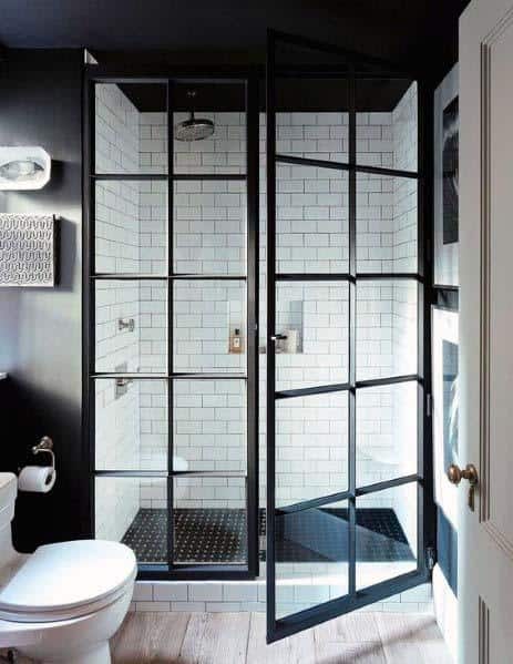 Modern bathroom with black-framed glass shower doors and white subway tiles.