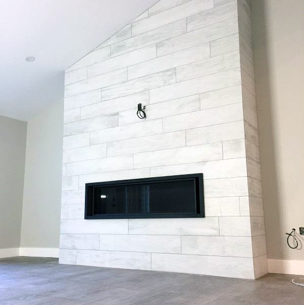 Modern fireplace with white wood-look tiles and a sleek black linear gas insert.