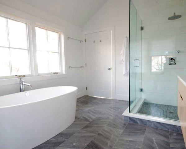 Modern bathroom with a freestanding tub, glass shower, large windows, and grey tiled floor