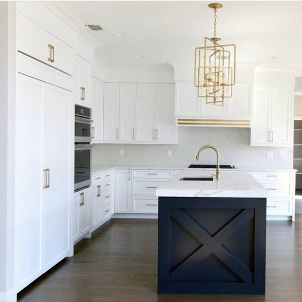 Stunning kitchen with a geometric gold pendant light above a white and navy island, complemented by sleek white cabinetry and dark wood flooring