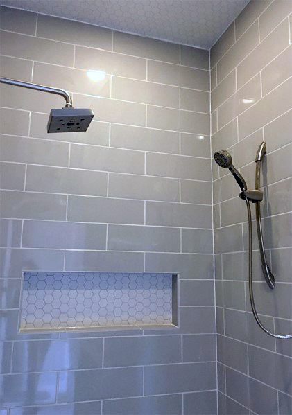 Shower with gray subway tiles, hexagonal tile niche, and dual showerheads.