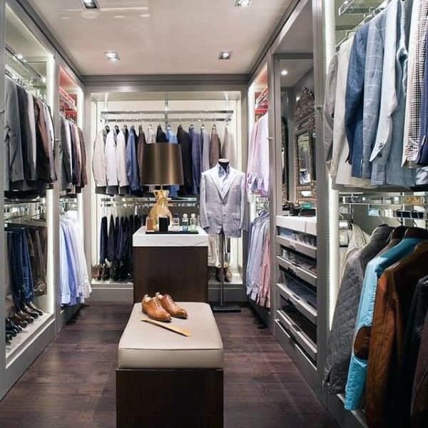 A luxurious walk-in closet with suits, shirts, shoes, and accessories neatly organized on shelves and racks