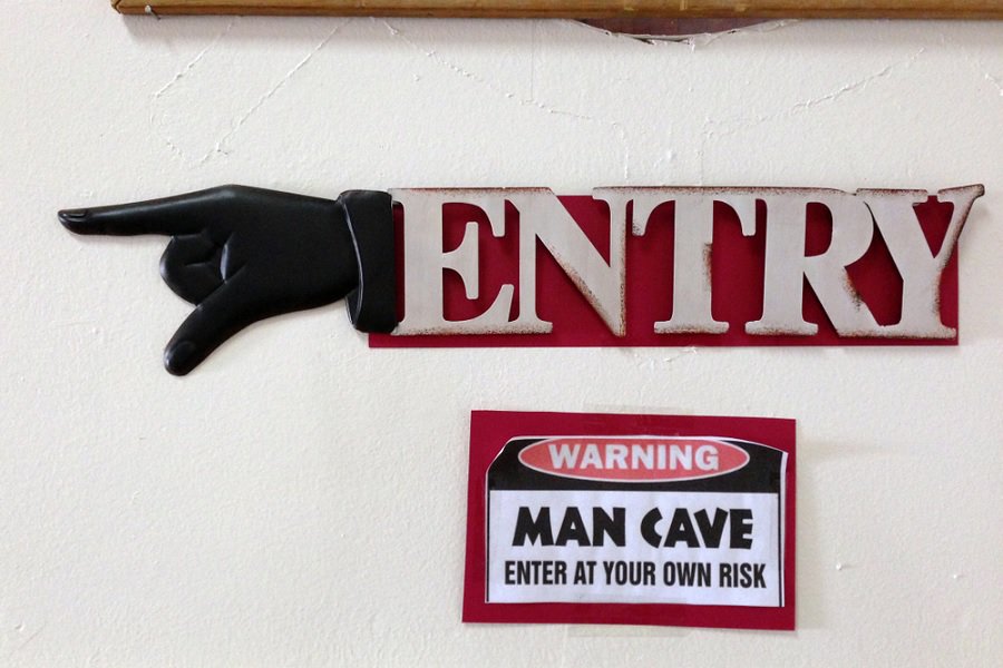 Man cave entry sign with pointing hand and warning to enter at your own risk.