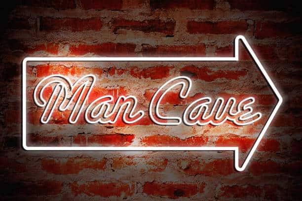 Neon-style "Man Cave" sign with an arrow on a brick wall background.