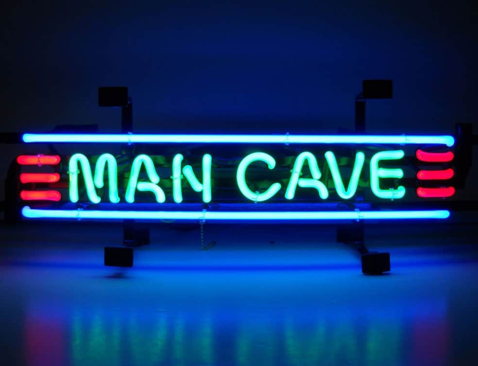 Green and blue neon "Man Cave" sign with red accents on a dark background.