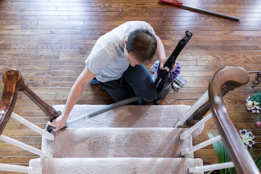 man cleaning carpet on stairs