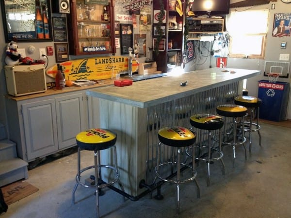 Garage bar with Landshark decor, metal stools, concrete countertop, and sports-themed accents.