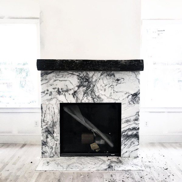 White marble fireplace with bold black veining and a dark wooden mantel.