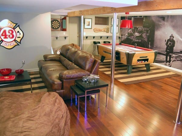 Midcentury modern mancave with leather sofa, foosball table, dartboard, and wood flooring.