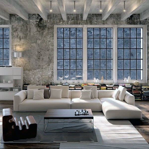 Living room with modern white sectional sofa, exposed concrete wall, and large industrial windows.