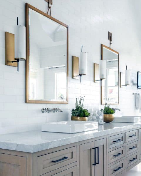 Large bathroom with double vanity, wooden cabinets, brass sconces, and rectangular mirrors.