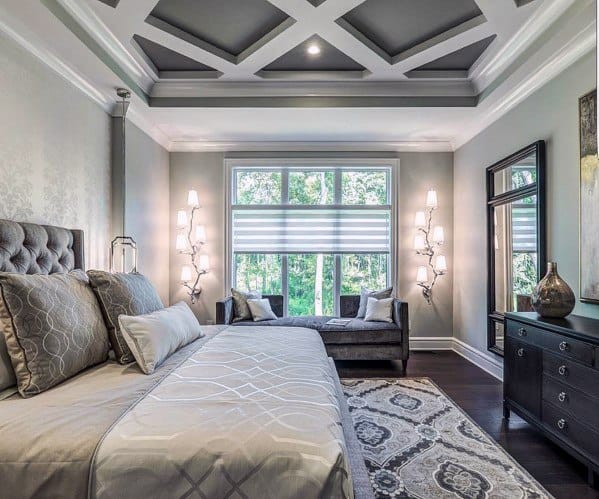 Elegant bedroom with coffered ceiling, tufted bed, gray accents, and modern wall lights.