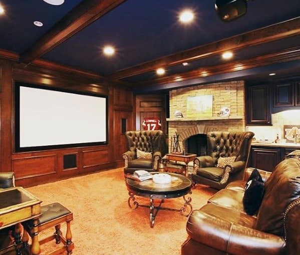 Home theater with leather seating, wood-paneled walls, large screen, and brick fireplace.