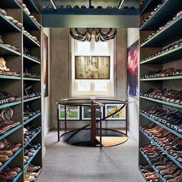 A stylish walk-in closet with shelves full of shoes and a spiral staircase leading down, lit by a large window