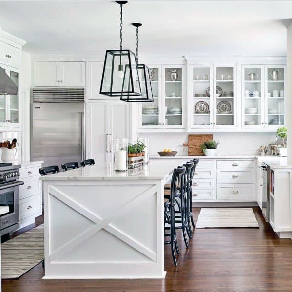 Bright kitchen featuring large metal and glass pendant lights above a white island, complemented by dark wood floors and sleek cabinetry